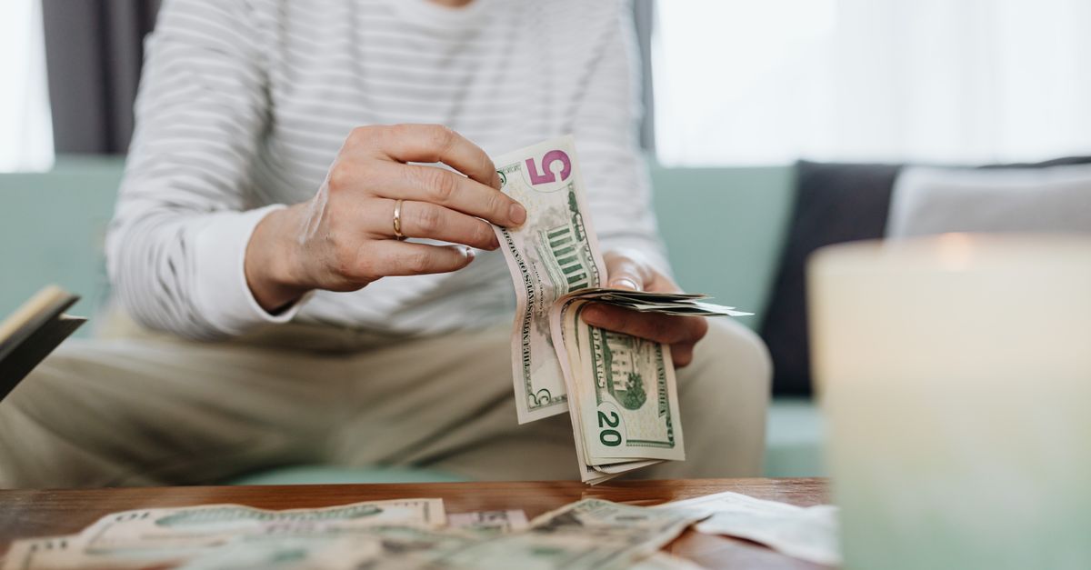 Close-up of hands counting dollar bills indoors, offering a personal finance theme.